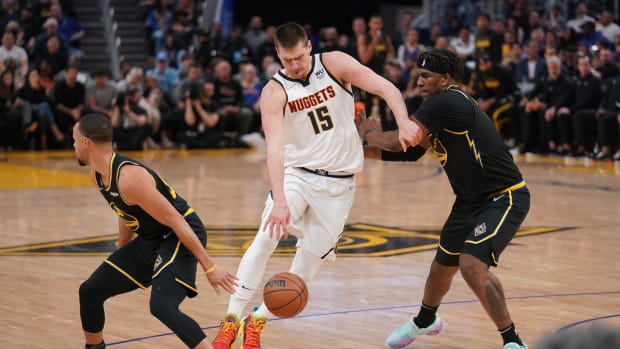 Apr 16, 2022; San Francisco, California, USA; Denver Nuggets center Nikola Jokic (15) dribbles the ball between Golden State Warriors guard Stephen Curry (30) and forward Kevon Looney (5) in the second quarter during game one of the first round for the 2022 NBA playoffs at the Chase Center. Mandatory Credit: Cary Edmondson-USA TODAY Sports